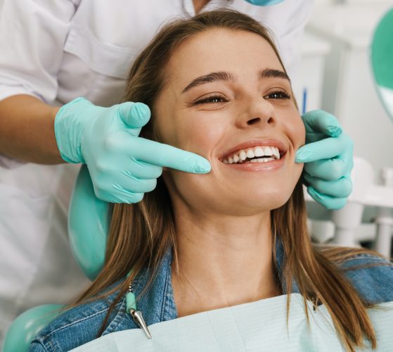 European young woman smiling while looking at mirror in dental clinic